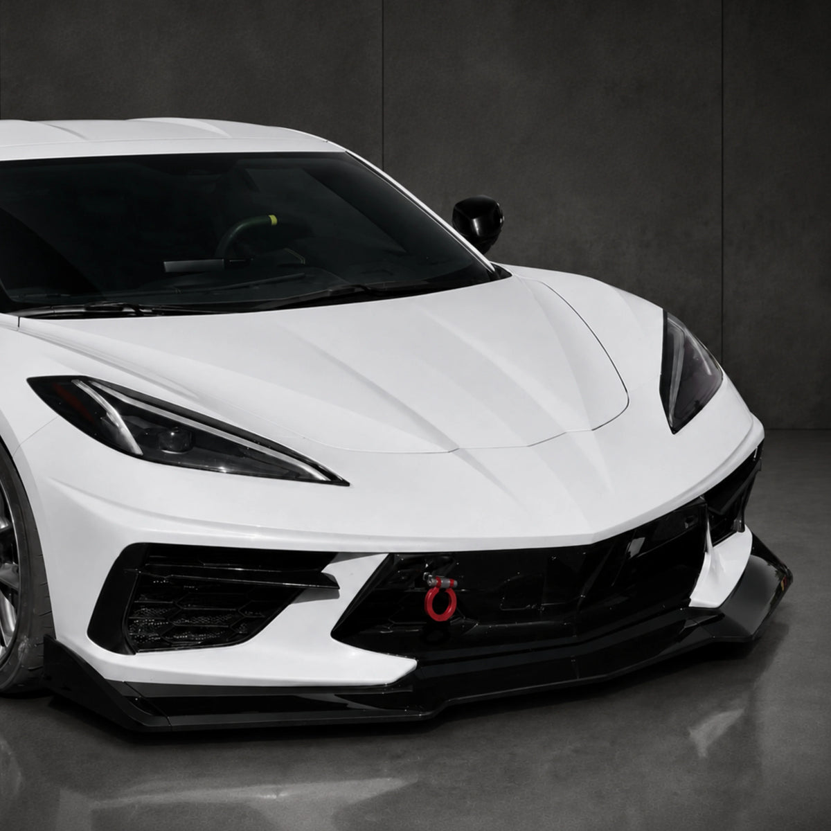 Angled view of black front splitter lip under the white front bumper
