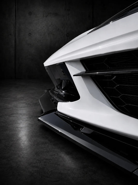 Close-up of black front splitter blade and side extensions on sports car