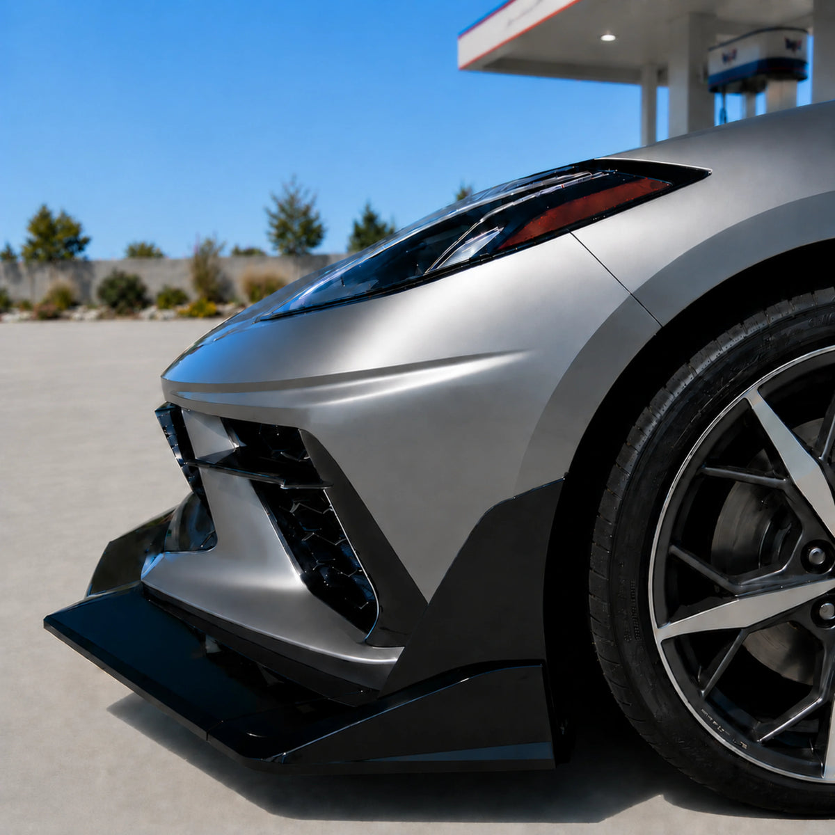 Black front splitter lip and side fin near front wheel on silver sports car